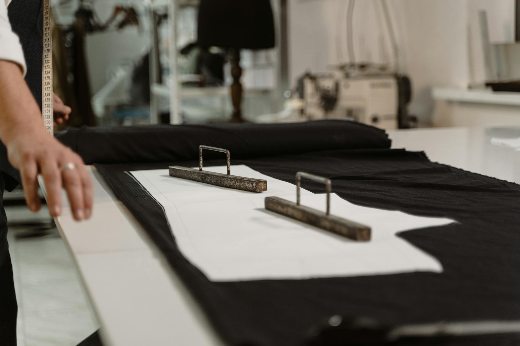 Close-up of a tailor measuring fabric with a tape in a sewing studio.