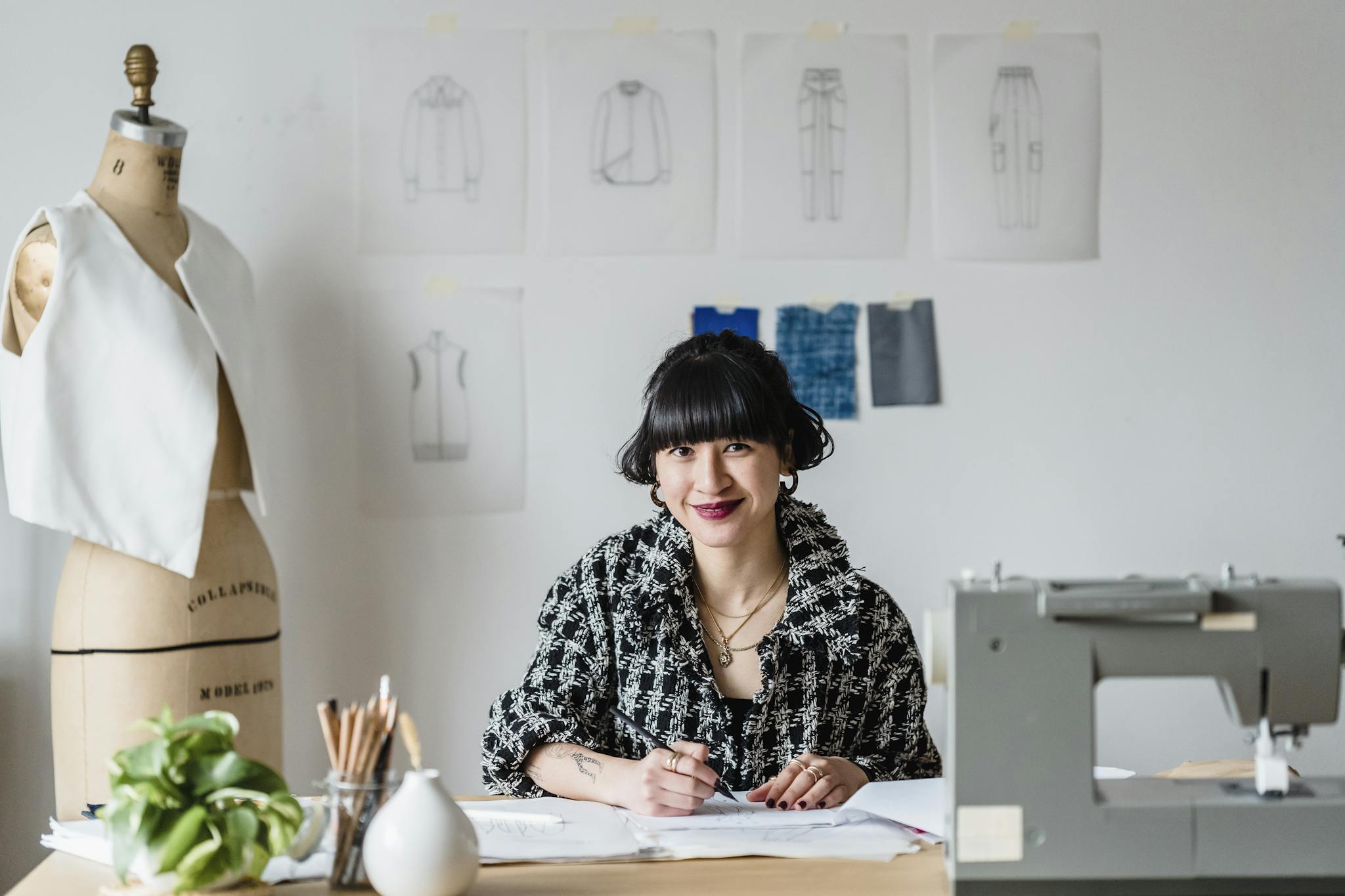 Creative fashion designer smiling at work in her studio, engaging in her craft.